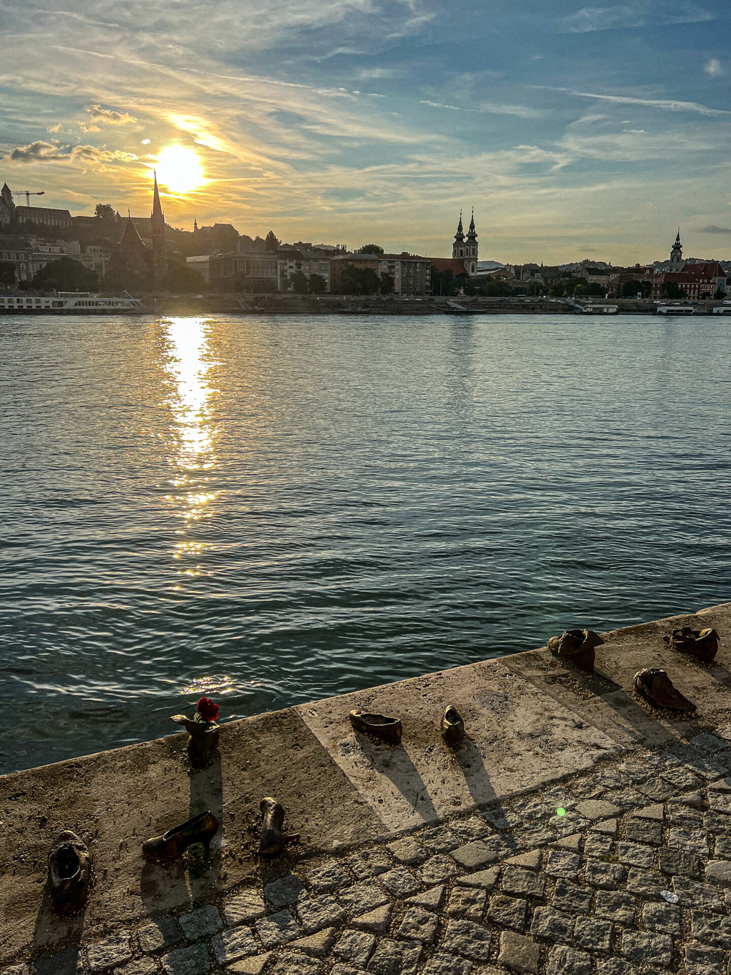 Budapest: Shoes on the Danube Bank with the sun setting in the distance